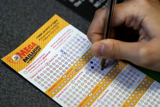 Um cliente preenche um bilhete de loteria da Mega Millions em uma loja de conveniência — Foto: Nam Y. Huh/AP